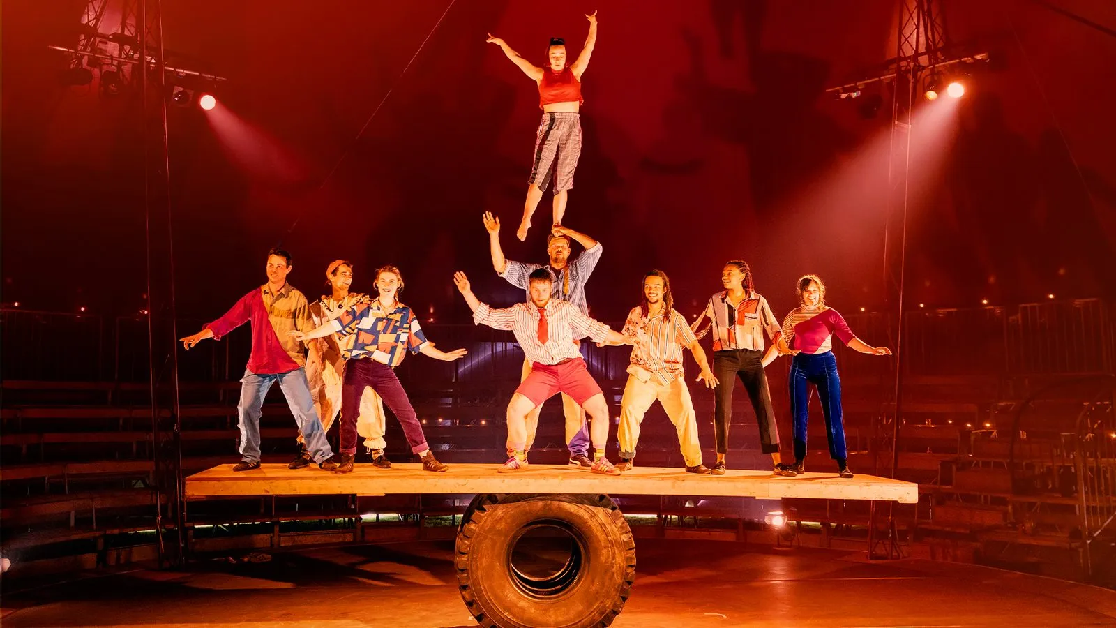 The Revel Puck troupe stacked in a human pyramid on a giant balance board in the big top